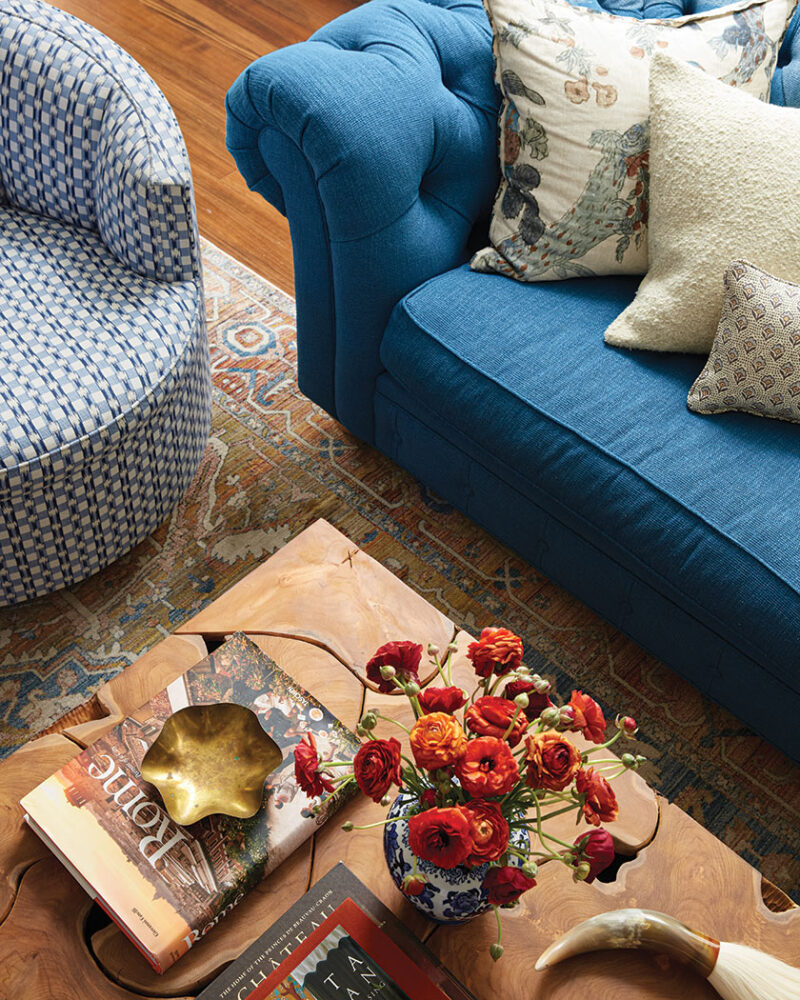 close up of living room showing rug and layered patterns of blue couch, blue and white side chair and throw pillows