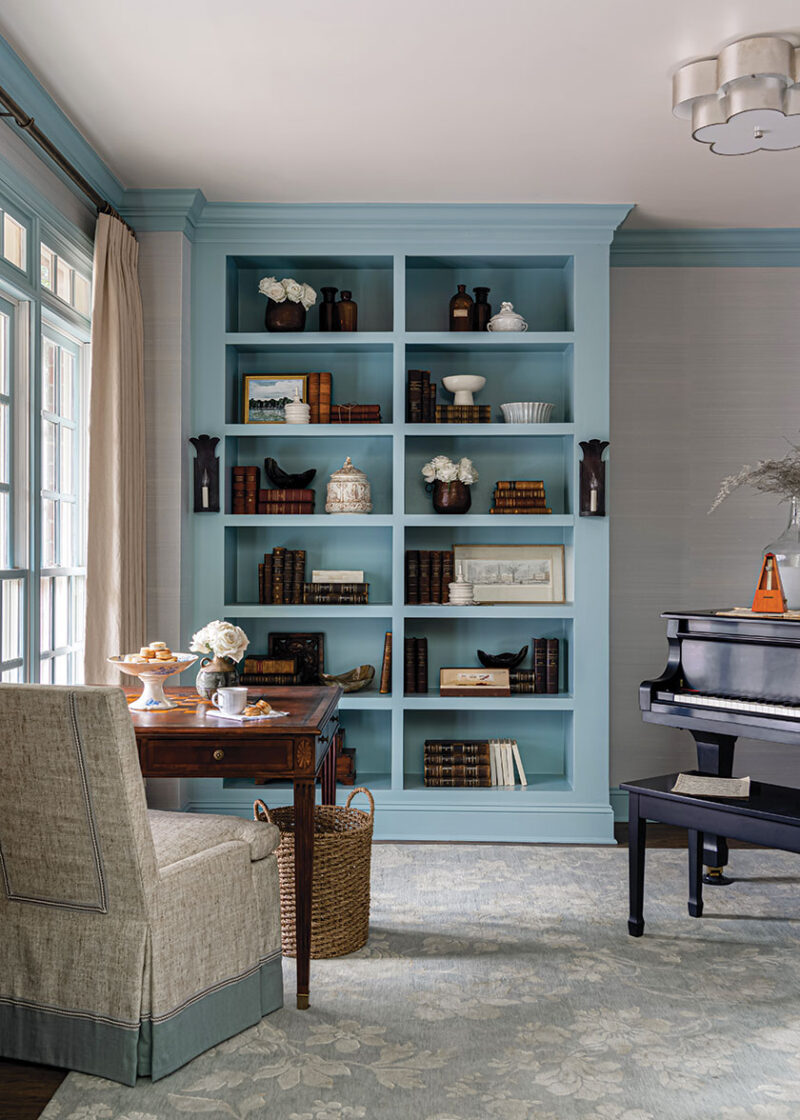 bookcase painted blue with French style chair upholstery in sitting room of renovated home