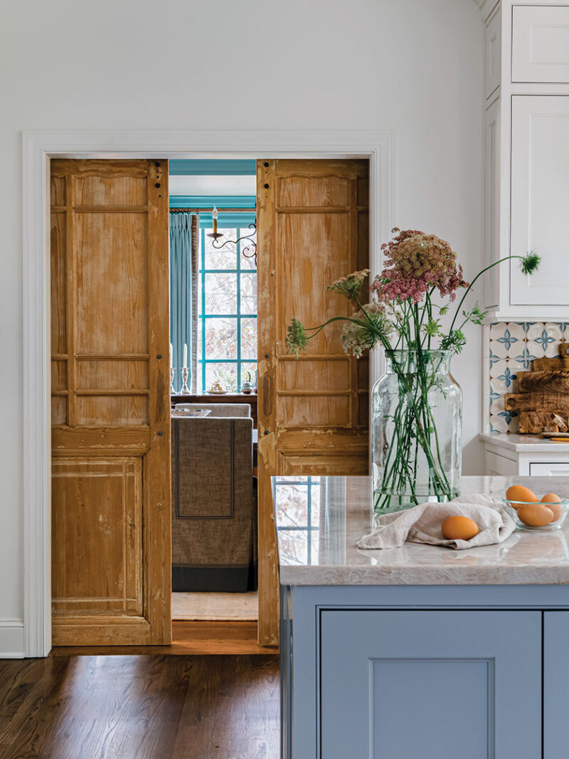 blue kitchen island and sliding wood doors in renovated French inspired kitchen