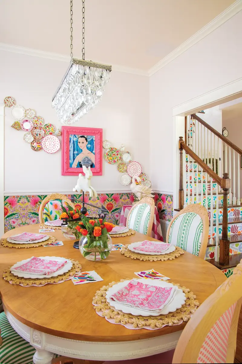 dining room with colorful wallpaper and gallery wall with painting and trail of colorful dishes