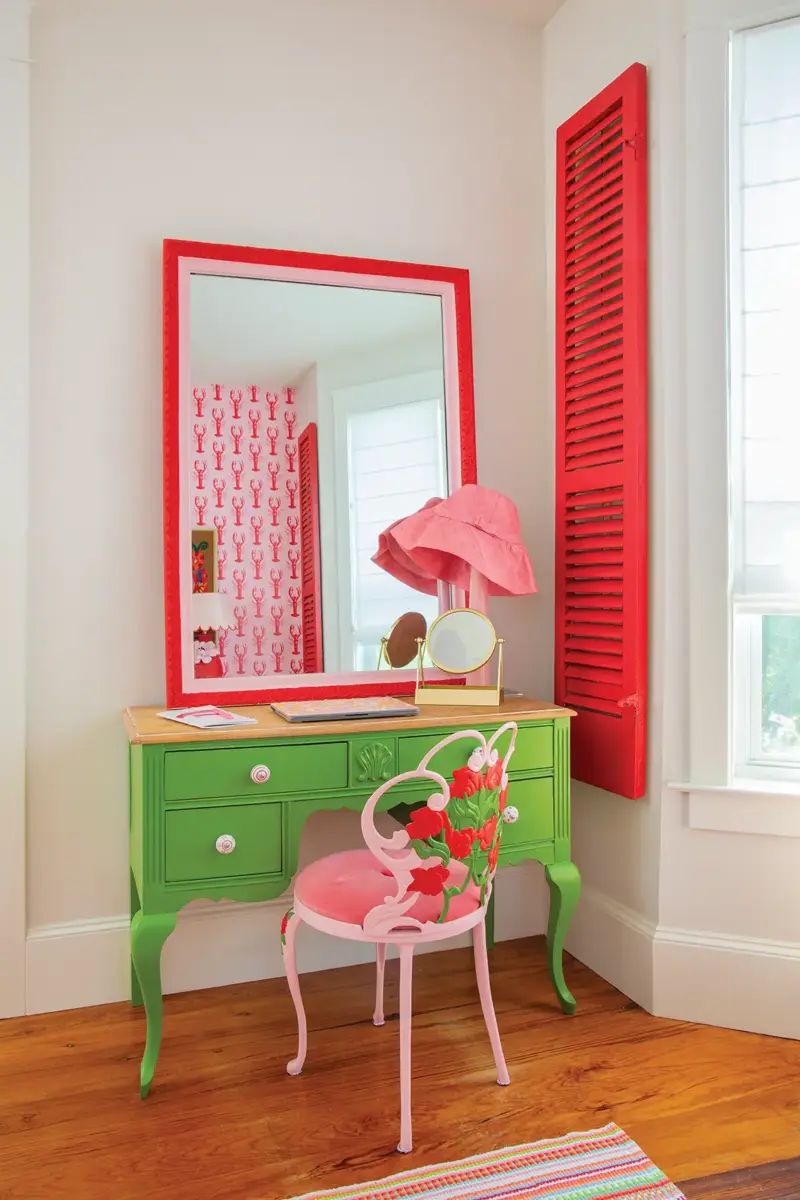 writing desk/vanity in guest bedroom with red framed mirror and green furniture