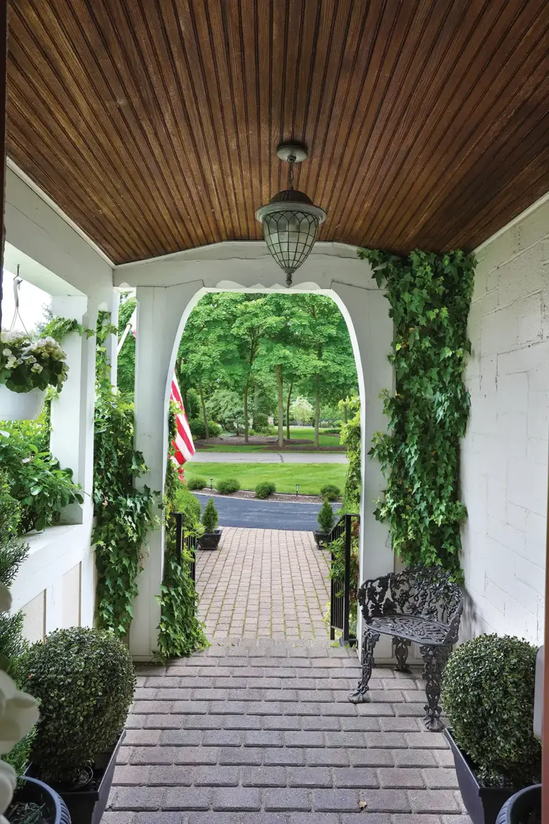 covered entryway with paved walkways, climbing ivy and wood overhang in 1926 Tudor home