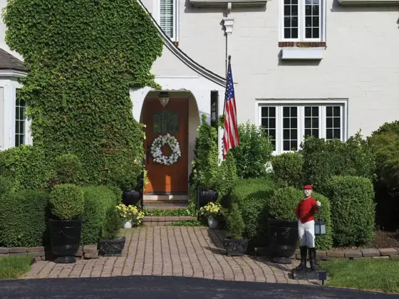 exterior view of 1926 Tudor home with floral wreath flag and sculpture of man holding a lamp