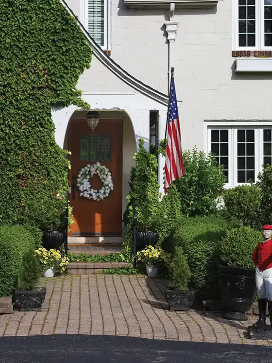 exterior view of 1926 Tudor home with floral wreath flag and sculpture of man holding a lamp